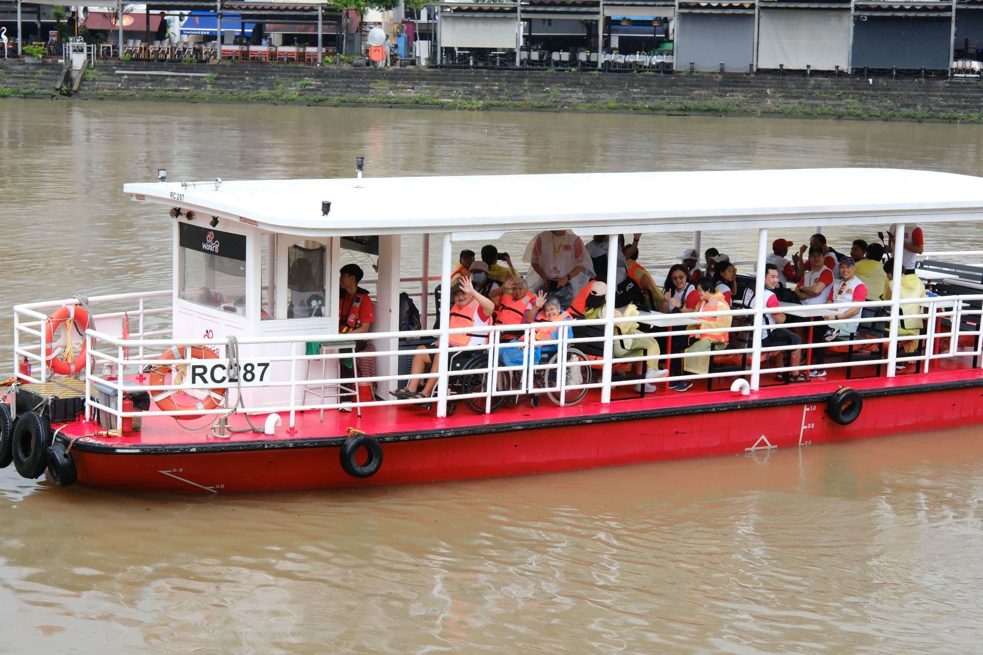 Wheelchair users and participants on board river cruise, waving happily