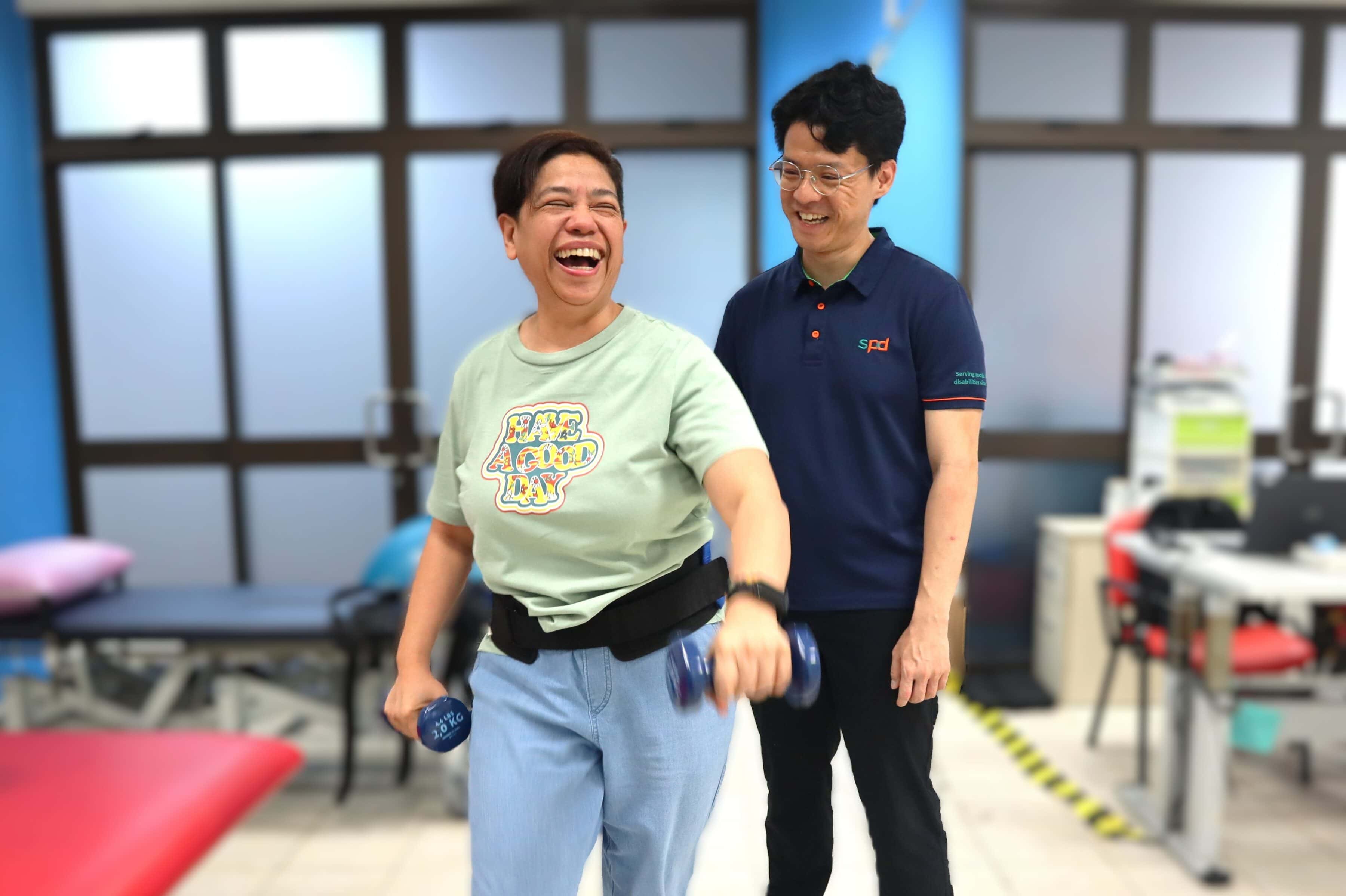 Chris guiding a client in exercising and stepping, both smiling cheerfully