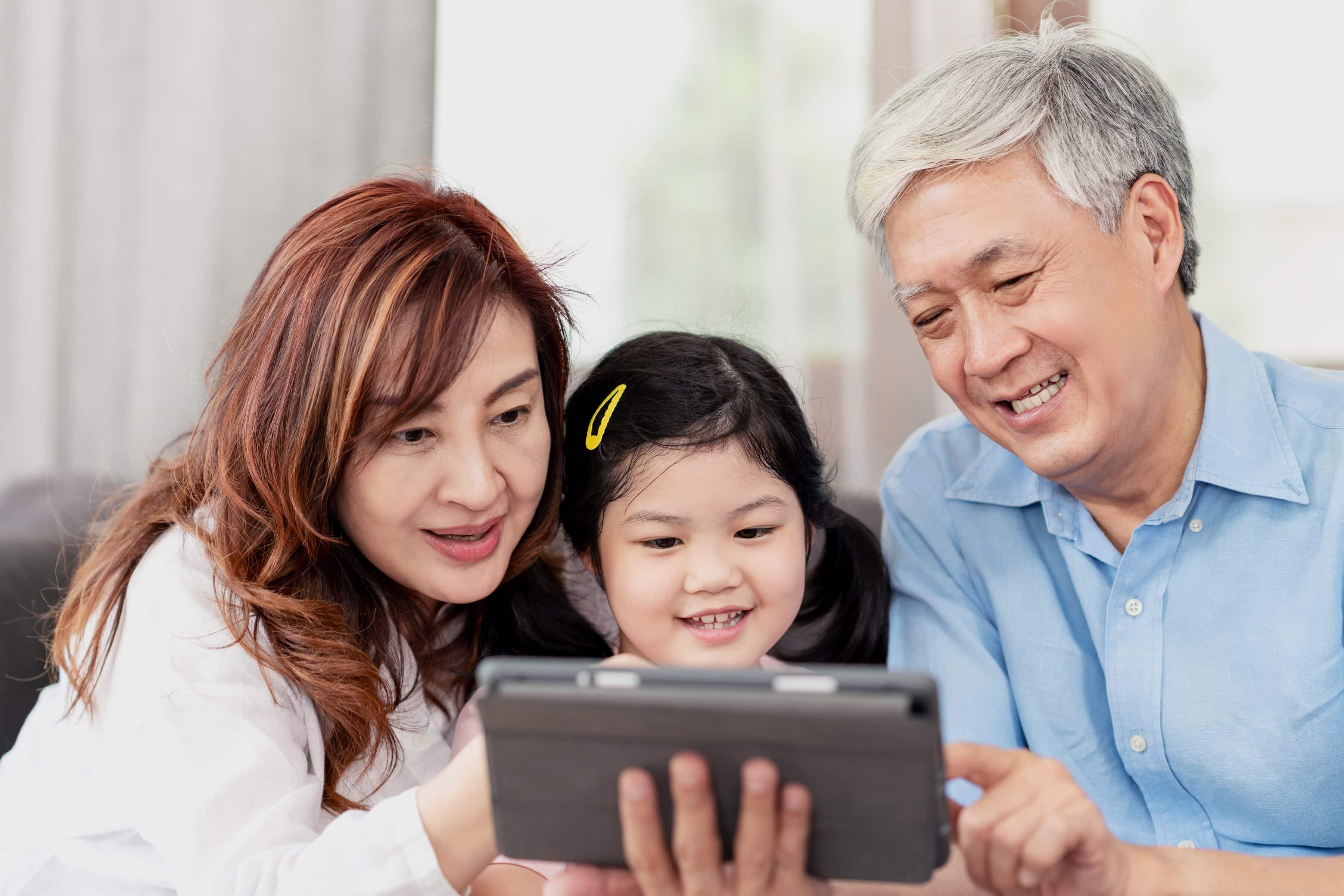 A woman, an elderly man and a young girl looking at a smartphone.