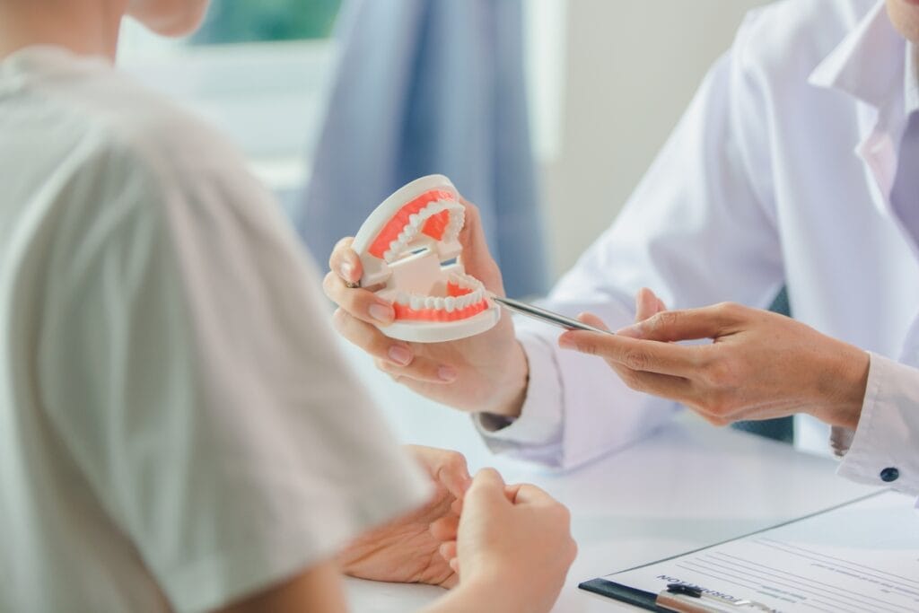 A dentist showing a patient a set of dental prosthesis