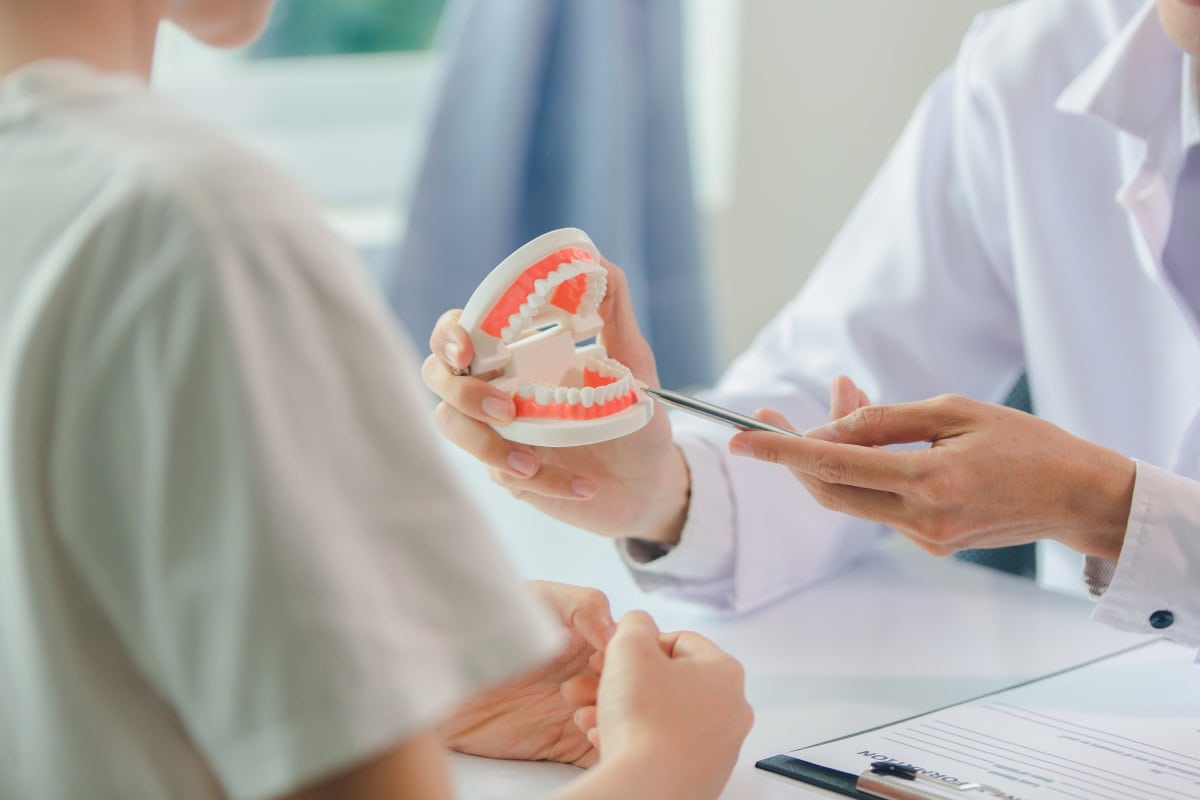 A dentist showing a patient a set of dental prosthesis
