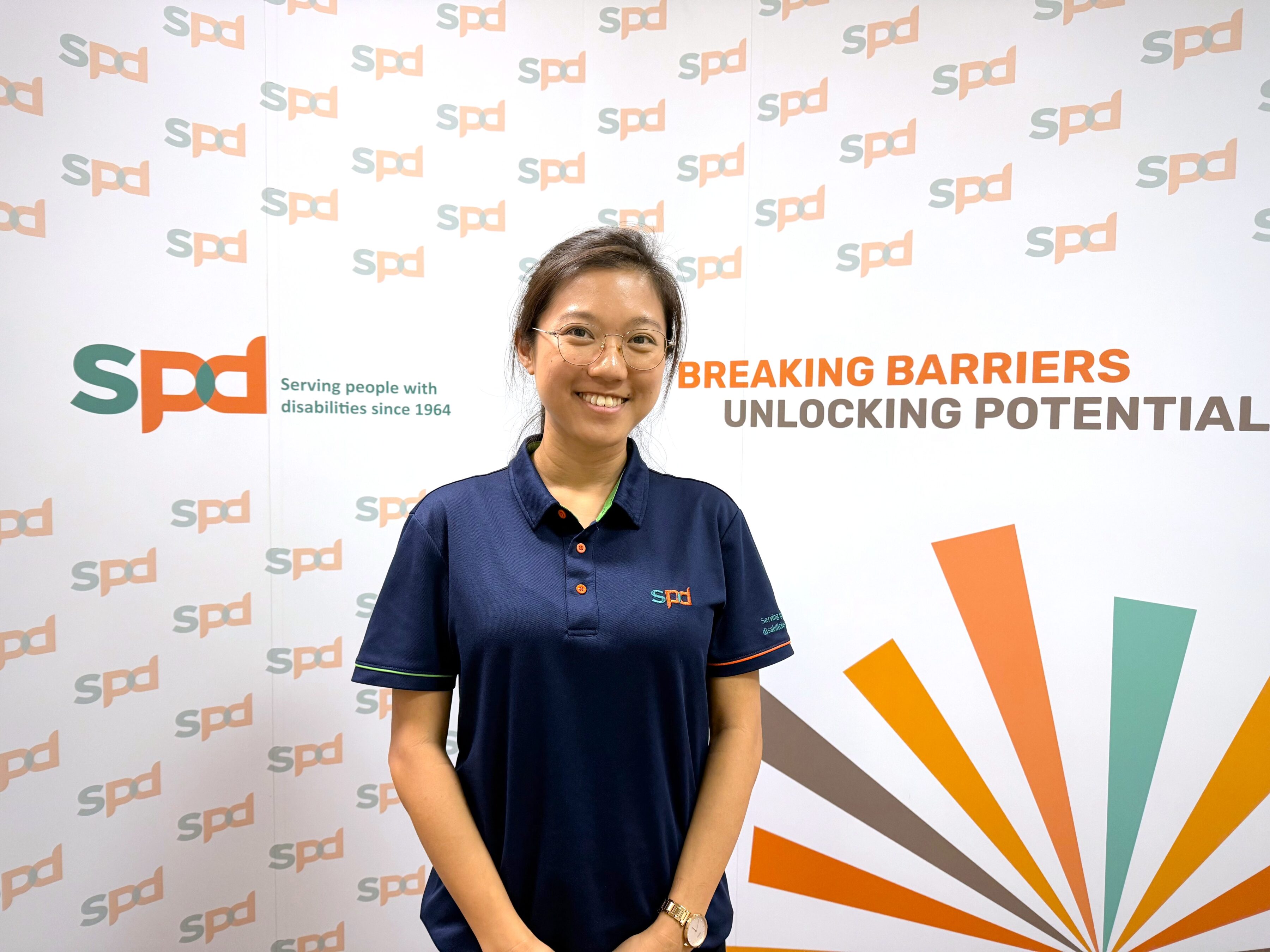 Jia Yi against a backdrop that includes S P D's logo and text 'Breaking barriers unlocking potentials'