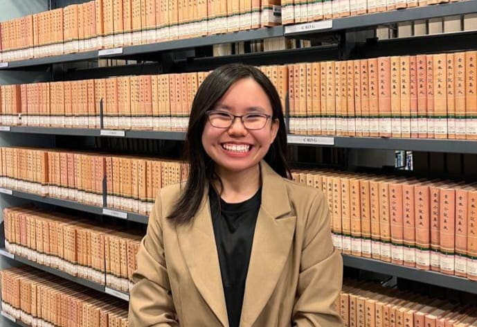 Turning Self-Doubt into Purpose, Youth with Vision Loss Hopes to Help Others Find Strength 6 Cindy smiling brightly, behind her are neatly arranged shelves of books