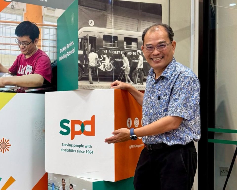 Strength in Community: How a Donor’s In-Kind Donation Sparked a Chain of Giving 6 Mr Ong at the S P D Ability Centre lobby, posing with a cube with S P D's logo on it.