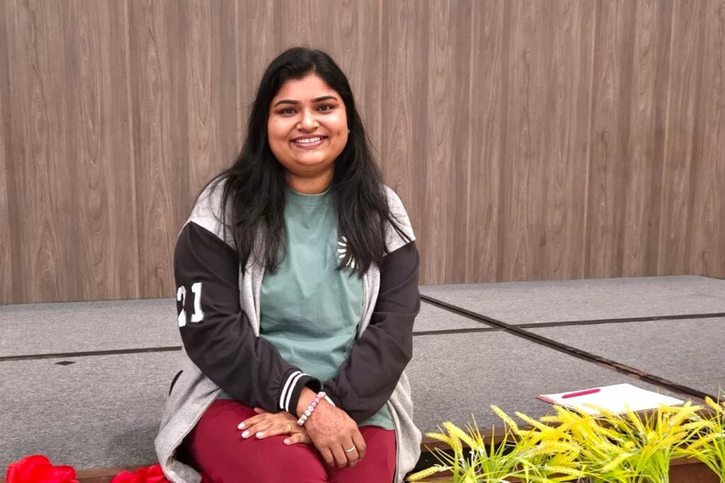 Strength in Community: She Came to Help Others and Found Support Herself 7 Sindhu seated at a stage area