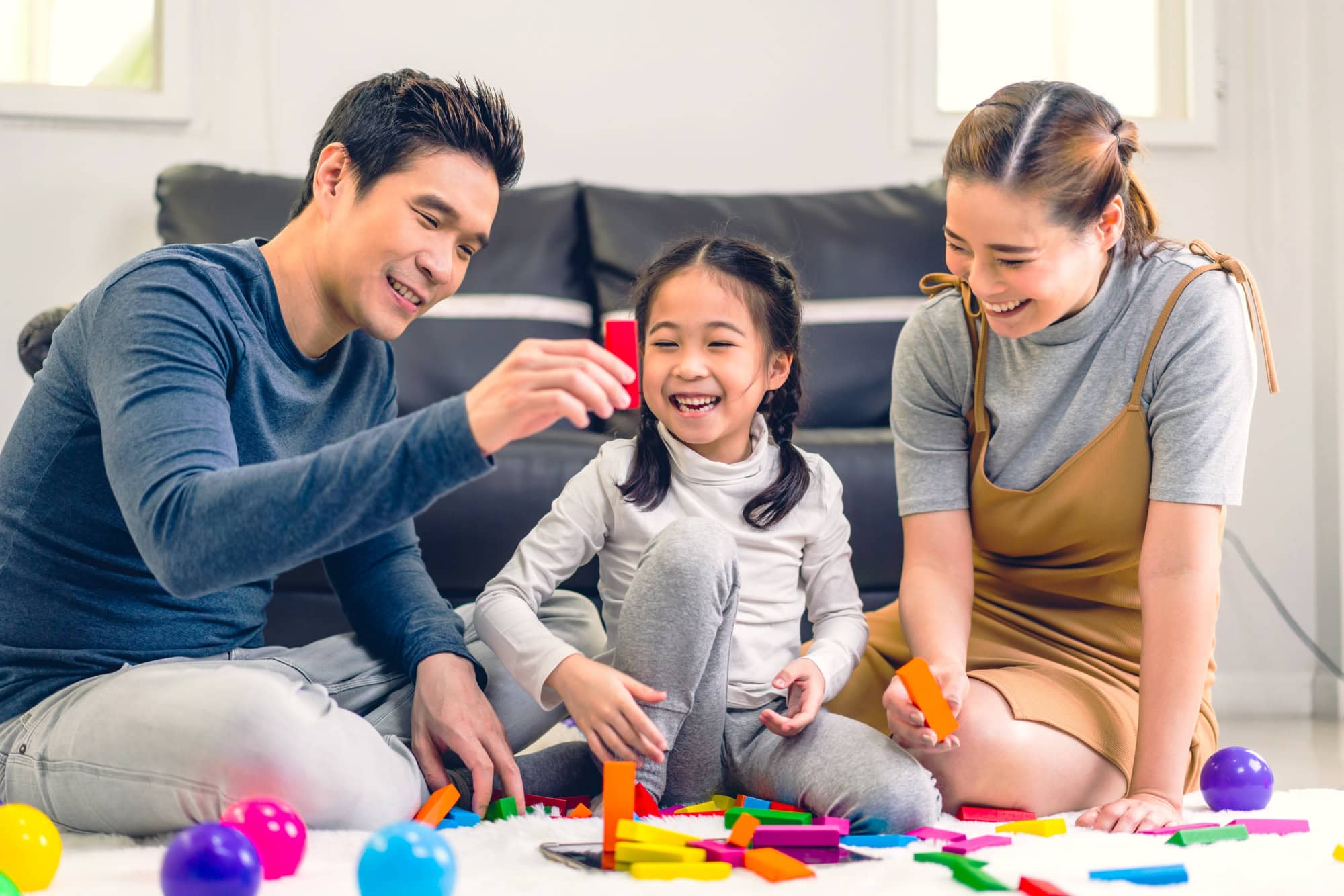 Parents and a child playing with colourful toy bricks
