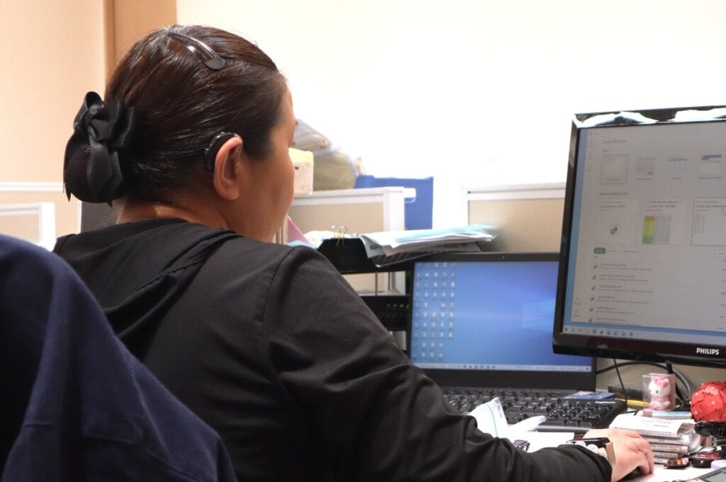 A person wearing a hearing aid looking at a computer screen