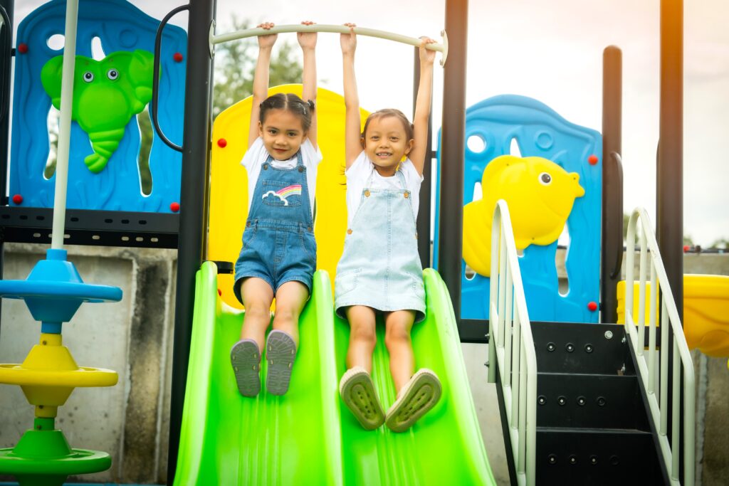 2 young girls playing happily on a playground slide