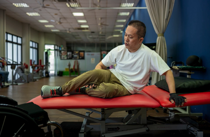 From setback to strength 2 Mr Wong on a therapy bed moving his legs with his arms