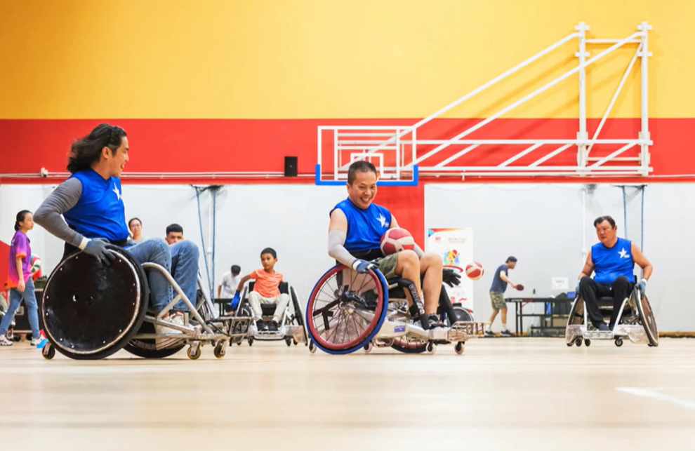 From setback to strength 4 In a wheelchair rugby game, Mr Wong has a ball on his lap as an opponent wheels towards him